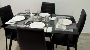 A dining area with a table set for four, black chairs, and a decorative blue elephant on the wall.