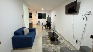 A modern living room with a blue sofa, a coffee table, and a TV mounted on the wall.