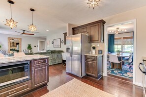 A modern kitchen with dark wood cabinets, a stainless steel refrigerator, a built-in microwave, and a ceiling fan. - Tropical Papaya -3-BR house in National Hills Augusta/Hot Tub/Pool Table/Yard (Augusta)
