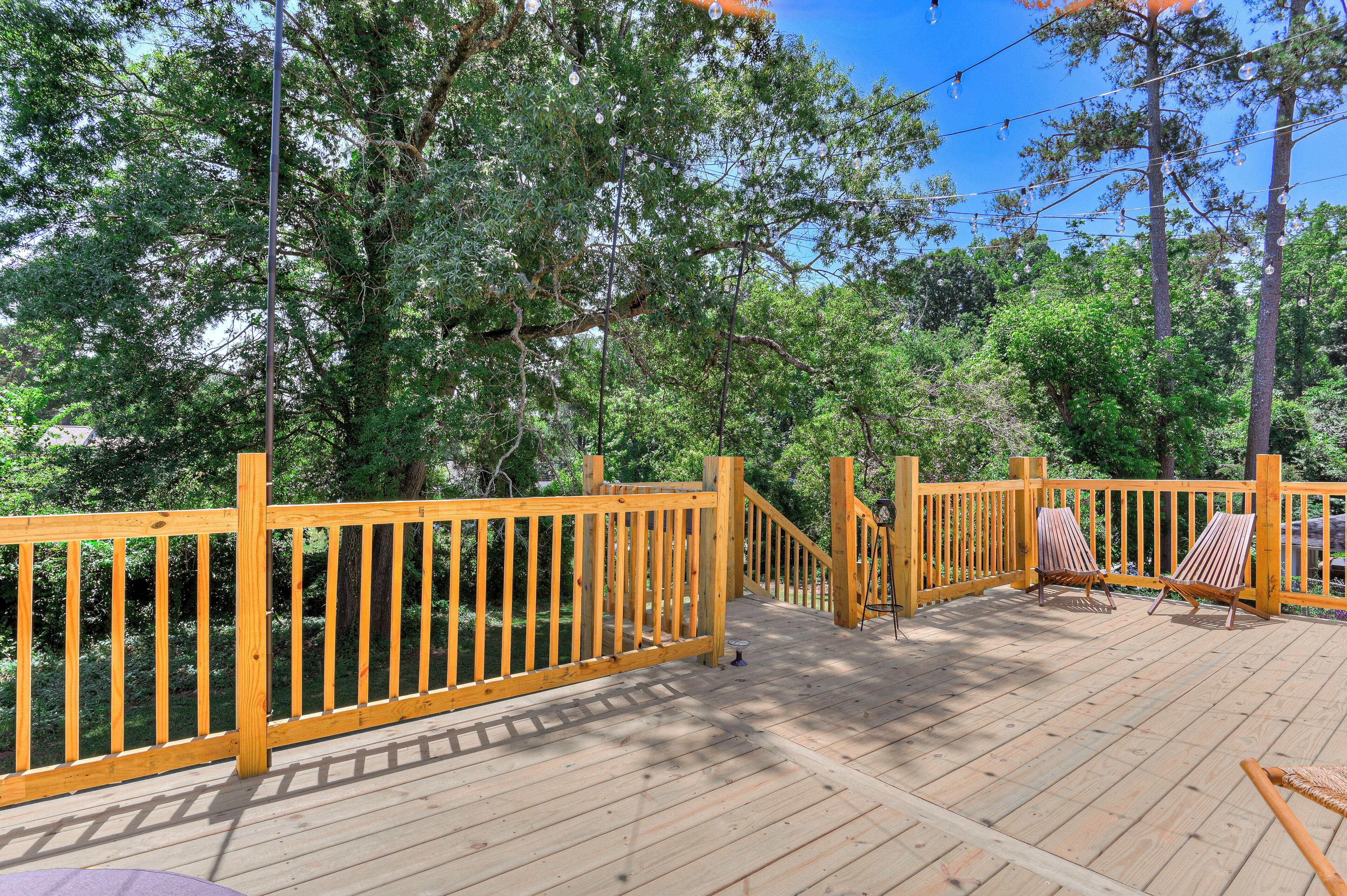 A wooden deck with a railing, two chairs, and a small table.