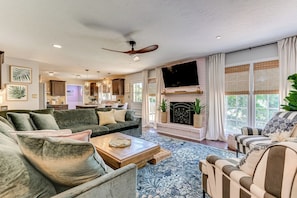 A spacious living room with a fireplace, a television, and a kitchen in the background. - Tropical Papaya -3-BR house in National Hills Augusta/Hot Tub/Pool Table/Yard (Augusta)