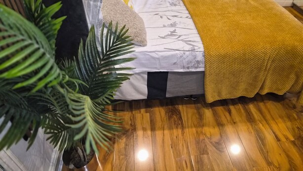 A bedroom with a bed, a potted plant, and a wooden floor. - 3 min walk to tube for central London (London)