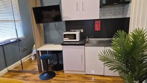 A compact kitchen with a microwave, sink, and white cabinets. - 3 min walk to tube for central London (London)