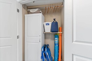 A closet with a white door, wooden hangers, a shelf with storage bins, and blue and orange items. - Bayfront Condo with Peaceful Water Views (Fort Walton Beach)