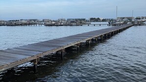 En träbrygga som sträcker sig ut i stilla vatten, med båtar förtöjda vid dess ände.