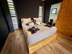 Ein Schlafzimmer mit einem Holzbettgestell, einem großen Fenster mit Jalousien und einem Spiegel an der Wand.