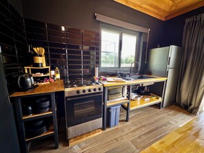 Eine kompakte Küche mit Herd, Backofen und Spüle, Holzarbeitsplatten und einem Fenster für natürliches Licht.