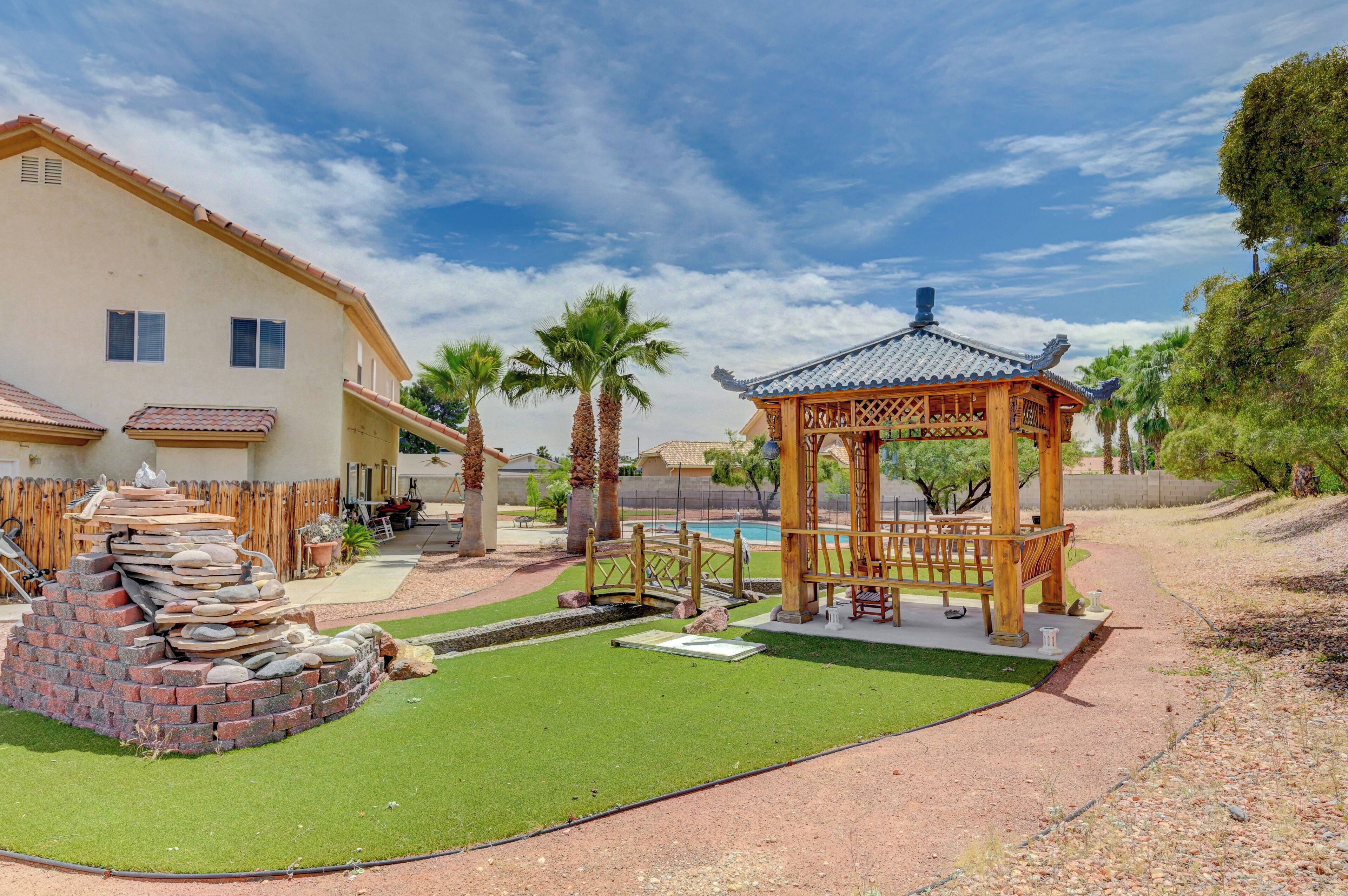 Um pátio com um gazebo, uma estrutura de tijolos e uma piscina.