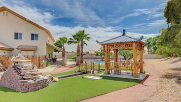Um pátio com um gazebo, uma estrutura de tijolos e uma piscina.