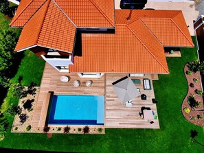 Ein modernes Haus mit Swimmingpool, Gartenmöbeln und einem gepflegten Garten.