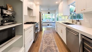 A modern kitchen with white cabinetry, stainless steel appliances, and a central island. - Sunny Designer Mill Valley Home; great for kids, walk to park, downtown & trails (Mill Valley)