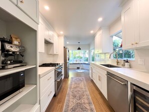 A modern kitchen with white cabinetry, stainless steel appliances, and a central island. - Sunny Designer Mill Valley Home; great for kids, walk to park, downtown & trails (Mill Valley)