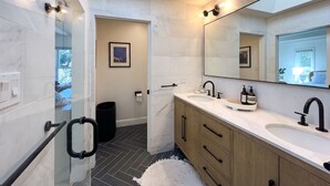 A modern bathroom with a large mirror, dual sinks, and a black trash bin. - Sunny Designer Mill Valley Home; great for kids, walk to park, downtown & trails (Mill Valley)