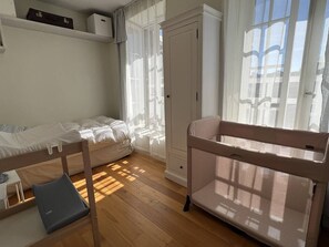 Ein Zimmer mit Etagenbett, Babybett, Schreibtisch und Kleiderschrank.