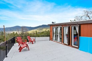 Ein Balkon mit roten Stühlen, Blick auf Berge und ein Gebäude mit großen Fenstern.