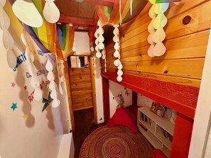 A bunk bed room with a red and white color scheme, a small circular rug, and a shelf with books. - Camp Coleman-Theater Room - Game Room - Sleeps 29 (Oakhurst)