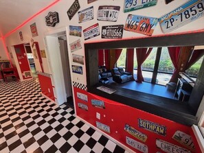 A diner with a checkered floor, a booth seating area, and various license plates on the walls. - Camp Coleman-Theater Room - Game Room - Sleeps 29 (Oakhurst)