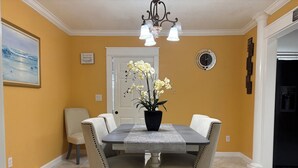 A dining area with a table, chairs, a potted plant, a clock, and a door. - 3-bedroom apartment in peaceful Stuart with cool AC (Stuart)