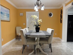 A dining area with a table, chairs, a potted plant, a clock, and a door. - 3-bedroom apartment in peaceful Stuart with cool AC (Stuart)