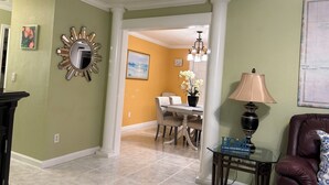 A living room with a dining area, a lamp, and a map on the wall. - 3-bedroom apartment in peaceful Stuart with cool AC (Stuart)