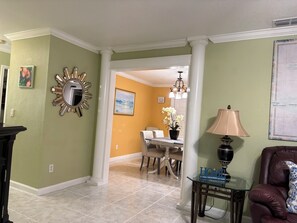 A living room with a dining area, a lamp, and a map on the wall. - 3-bedroom apartment in peaceful Stuart with cool AC (Stuart)