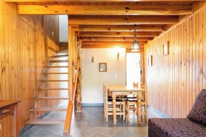 Ein Holzinnenraum mit einer Treppe, einem Essbereich mit Tisch und Stühlen sowie einem Sofa.
