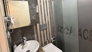 Un baño con lavamanos, espejo, inodoro y zona de ducha.