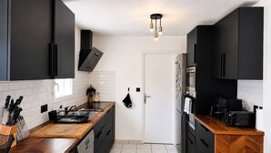 Eine moderne Küche mit schwarzen Schränken, einer Holzarbeitsplatte, einem eingebauten Ofen und einer Kaffeemaschine.