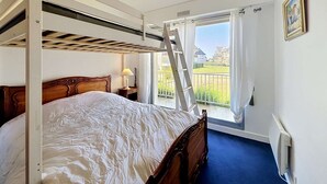 A bunk bed with a ladder, a bedside table with a lamp, a window with curtains, and a radiator. - QUIBERON - 2 rooms - 55m2 - Sea view (QUIBERON)