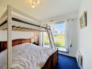 A bunk bed with a ladder, a bedside table with a lamp, a window with curtains, and a radiator. - QUIBERON - 2 rooms - 55m2 - Sea view (QUIBERON)