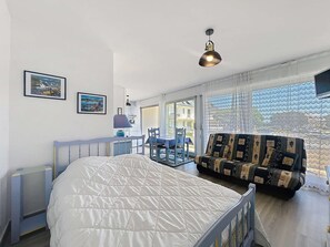 Ein Schlafzimmer mit Bett, Schreibtisch, Stuhl, Sofa und einem Balkon mit Blick.