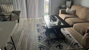 Een woonkamer met een bank, een bijzettafeltje en een lamp.