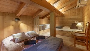 A wooden cabin interior with a bed, a bench, a table, and a hanging light fixture. - Le Petit Riondet - SAINT NICOLAS LA CHAPELLE (SAINT NICOLAS LA CHAPELLE)