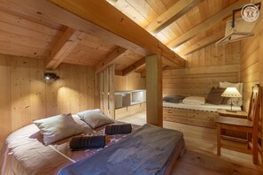 A wooden cabin interior with a bed, a bench, a table, and a hanging light fixture. - Le Petit Riondet - SAINT NICOLAS LA CHAPELLE (SAINT NICOLAS LA CHAPELLE)