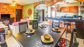 En matplats med ett bord för fyra personer, ett kök med träskåp och ett vardagsrum med en soffa och en tv.