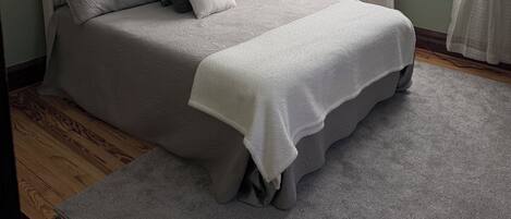 Une chambre à coucher avec un lit, un ventilateur de plafond, une fenêtre avec des rideaux et une vue sur l’extérieur.