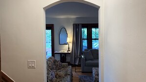 Un couloir avec un escalier, un salon avec un canapé et une lampe, et un luminaire au plafond.