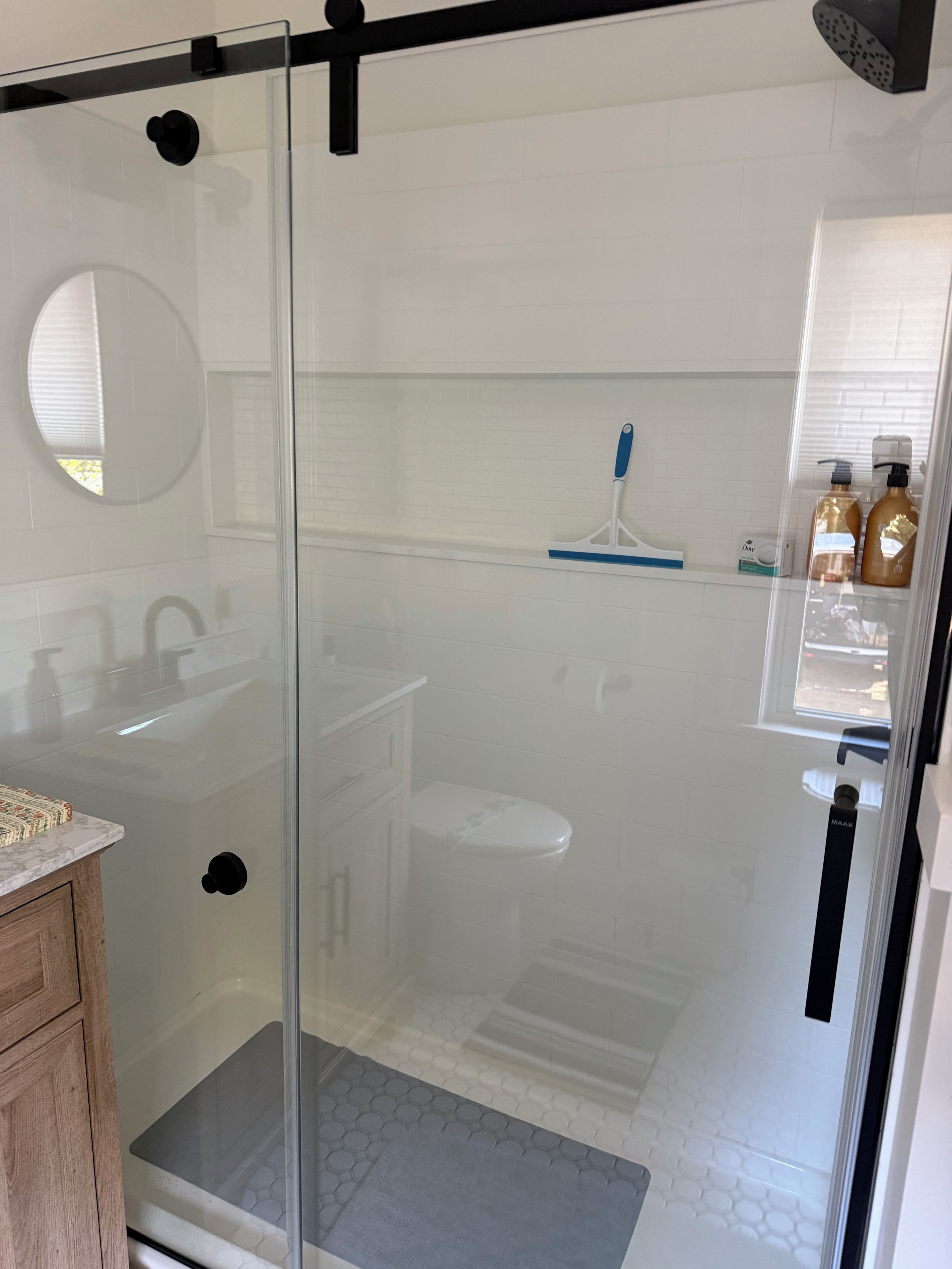 A modern bathroom with a glass shower enclosure, a toilet, and a vanity with a mirror.