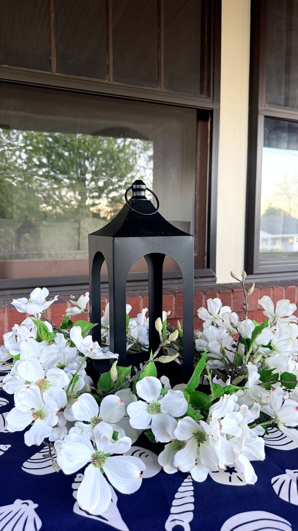 A lantern on a table surrounded by white flowers.