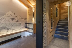 Ein modernes Interieur mit einer Steinwand, einer Holztreppe und Blick auf einen Berg.