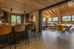 Eine moderne Küche mit Barhocker, einem Esstisch mit Stühlen und einer Couch.