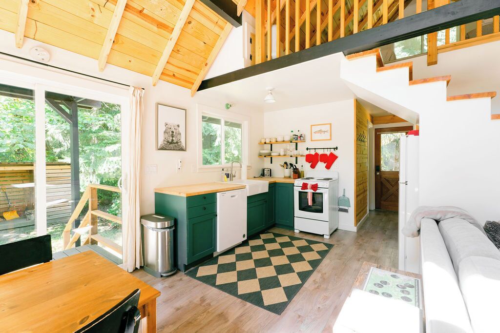 A cozy kitchen with wooden beams, a dining area, and a living space with a checkered floor.