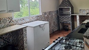 A kitchen with a gas stove, a refrigerator, a brick oven, and patterned tiles. - Sitio toa toa 2 (São roque)