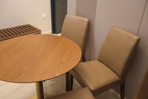 Una mesa redonda de madera con cuatro sillas de cuero color arena.
