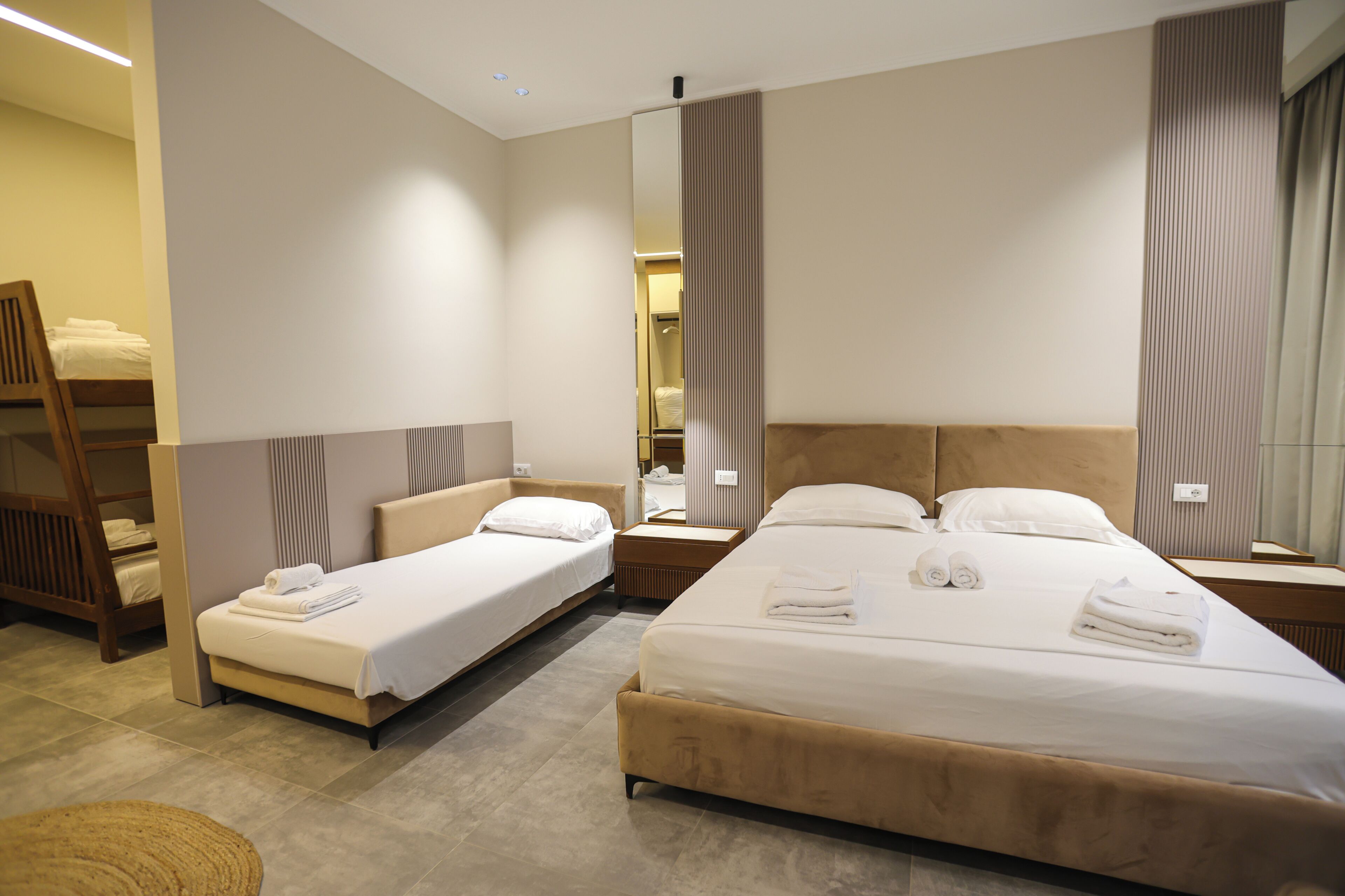 A hotel room with two beds, a large mirror, and a wooden chair.