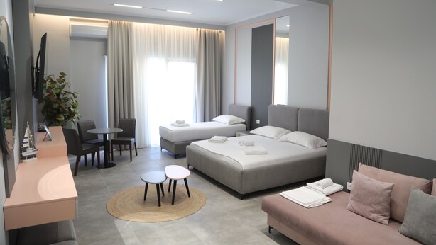 Una habitación de hotel moderna con una cama grande, un sofá, un escritorio y un comedor.