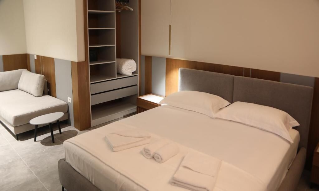 Quarto de hotel moderno com cama, área de estar e closet espaçoso.