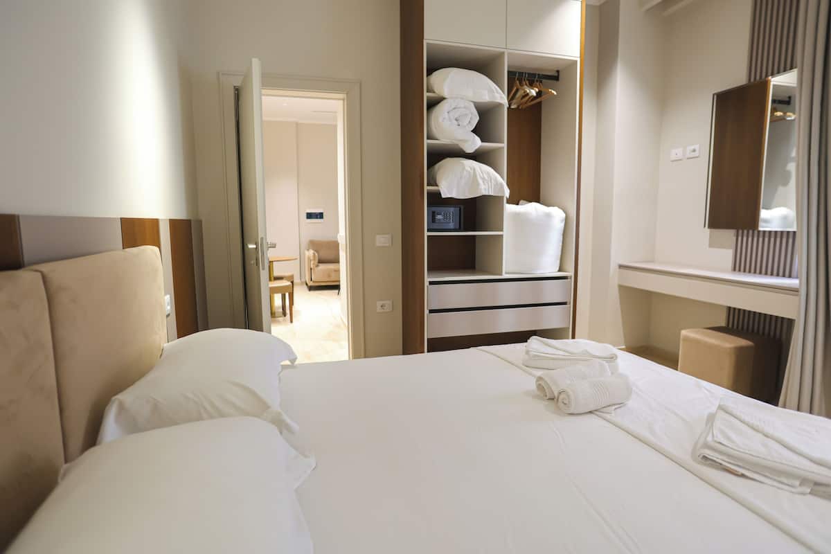 A hotel room with a bed, a wardrobe, a mirror, and a seating area.