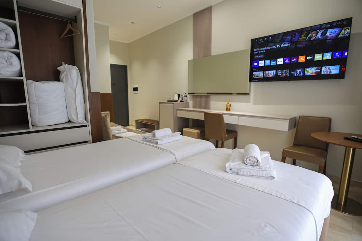 A hotel room with two beds, a desk, a TV, and a wardrobe.