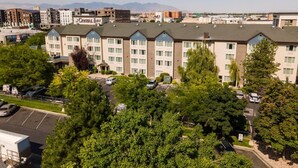 A multi-story hotel with a modern design, featuring a central courtyard with trees and a parking area. - 3 Modern Units | Explore Downtown Attractions | Free Breakfast, Parking, & Pool (Salt Lake County)